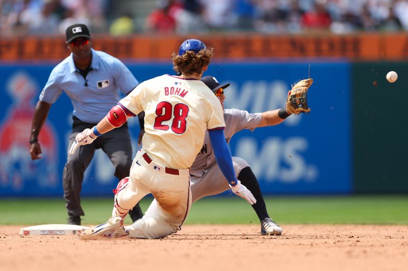 Jul 31, 2024; Philadelphia, Pennsylvania, USA;  Philadelphia Phillies third base Alec Bohm (28) slides into second base past New York Yankees shortstop Anthony Volpe (11) for a double during the eighth inning at Citizens Bank Park. Mandatory Credit: Bill Streicher-USA TODAY Sports