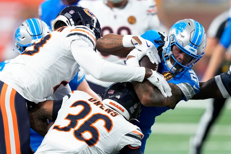 Detroit Lions running back Jahmyr Gibbs (26) tries to gain more yardage as Chicago Bears safety Jonathan Owens (36) and Tyrique Stevenson (29) defend during the first half of an NFL football game, Sunday, Nov. 17, 2024, in Detroit. (AP Photo/Carlos Osorio)