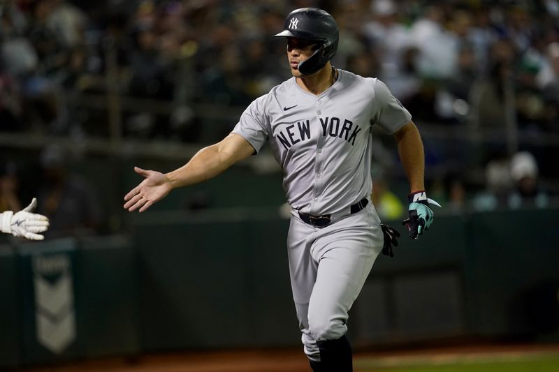 Sep 21, 2024; Oakland, California, USA; New York Yankees designated hitter Giancarlo Stanton (27) is congratulated by teammates after scoring a run against the Oakland Athletics in the seventh inning at the Oakland-Alameda County Coliseum. Mandatory Credit: Cary Edmondson-Imagn Images