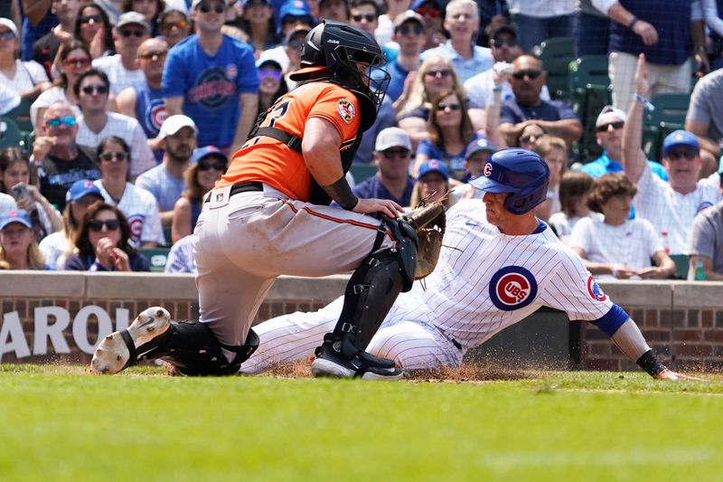 Jun 17, 2023; Chicago, Illinois, USA; Chicago Cubs catcher Yan Gomes (15) is safe at home plate as Baltimore Orioles catcher James McCann (27) makes a late tag during the fifth inning at Wrigley Field. Mandatory Credit: David Banks-USA TODAY Sports