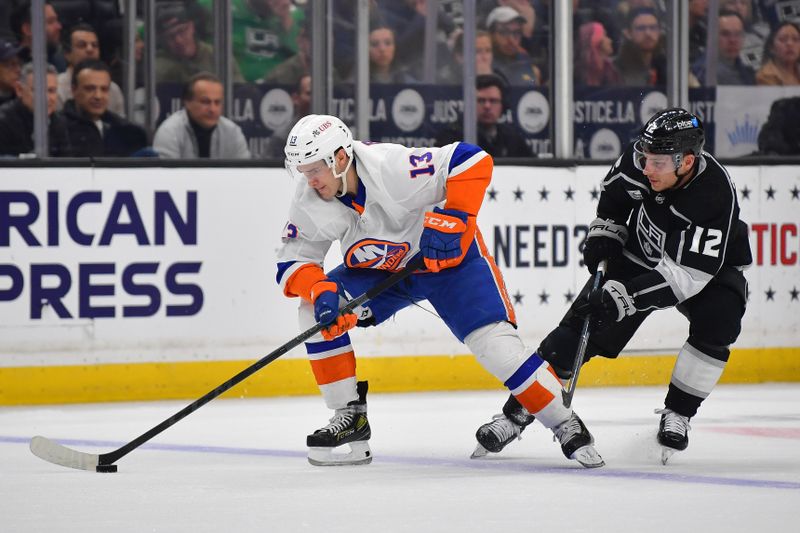 Mar 11, 2024; Los Angeles, California, USA; Los Angeles Kings left wing Trevor Moore (12) plays for the puck against New York Islanders center Mathew Barzal (13) during the second period at Crypto.com Arena. Mandatory Credit: Gary A. Vasquez-USA TODAY Sports