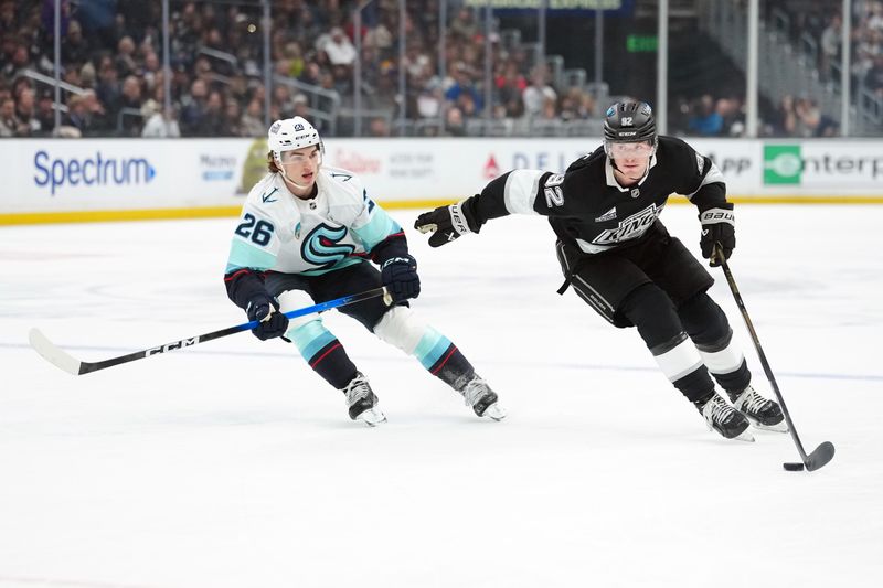 Dec 23, 2025; Los Angeles, California, USA; LA Kings defenseman Brandt Clarke (92) skates with the puck against Seattle Kraken center Ryan Winterton (26) in the second period at Crypto.com Arena. Mandatory Credit: Kirby Lee-Imagn Images