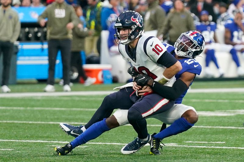 Houston Texans quarterback Davis Mills (10), left, is sacked by New York Giants cornerback Jason Pinnock (27) during the second half of an NFL football game, Sunday, Nov. 13, 2022, in East Rutherford, N.J. (AP Photo/Seth Wenig)