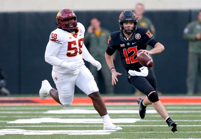 Nov 12, 2022; Stillwater, Oklahoma, USA;  Oklahoma State Cowboys quarterback Gunnar Gundy (12) scrambles as Iowa State Cyclones defensive lineman Isaiah Lee (58) pursues in the third quarter at Boone Pickens Stadium. OSU won 20-14. Mandatory Credit: Sarah Phipps-USA TODAY Sports