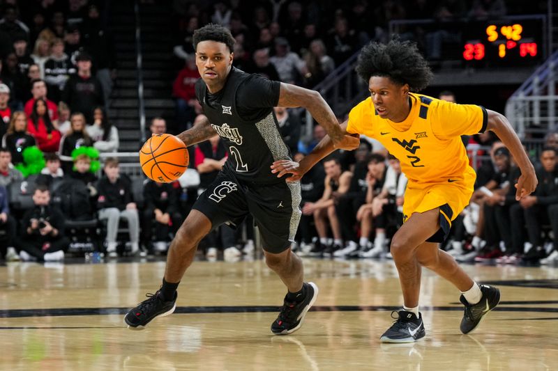 Feb 5, 2026; Cincinnati, Ohio, USA;  Cincinnati Bearcats guard Jizzle James (2) dribbles the ball against West Virginia Mountaineers guard Amir Jenkins (2) in the first half at Fifth Third Arena. Mandatory Credit: Aaron Doster-Imagn Images