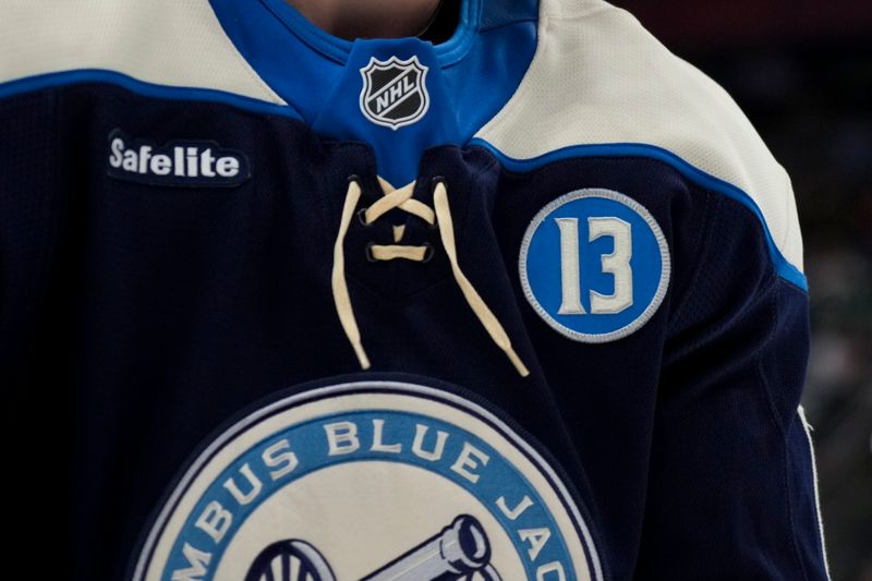 Nov 23, 2024; Columbus, Ohio, USA;  A patch honoring the late Johnny Gaudreau is seen on the jersey worn by a member of the Columbus Blue Jackets, during a stop in play against the Carolina Hurricanes in the third period at Nationwide Arena. Mandatory Credit: Aaron Doster-Imagn Images