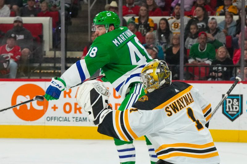 Mar 26, 2023; Raleigh, North Carolina, USA;  Carolina Hurricanes left wing Jordan Martinook (48) goes to tips the shot against Boston Bruins goaltender Jeremy Swayman (1) during the first period at PNC Arena. Mandatory Credit: James Guillory-USA TODAY Sports