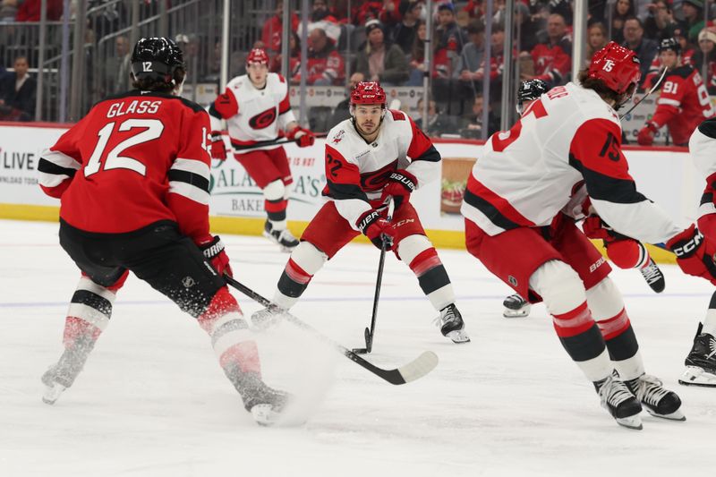 Jan 4, 2026; Newark, New Jersey, USA; Carolina Hurricanes center Logan Stankoven (22) skates with the puck as New Jersey Devils center Cody Glass (12) defends during the first period at Prudential Center. Mandatory Credit: Ed Mulholland-Imagn Images