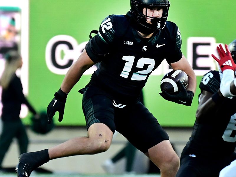 Nov 2, 2024; East Lansing, Michigan, USA;  Michigan State Spartans tight end Jack Velling (12) evades Indiana Hoosiers defensive back Jamier Johnson (9) during the third quarter at Spartan Stadium. Mandatory Credit: Dale Young-Imagn Images