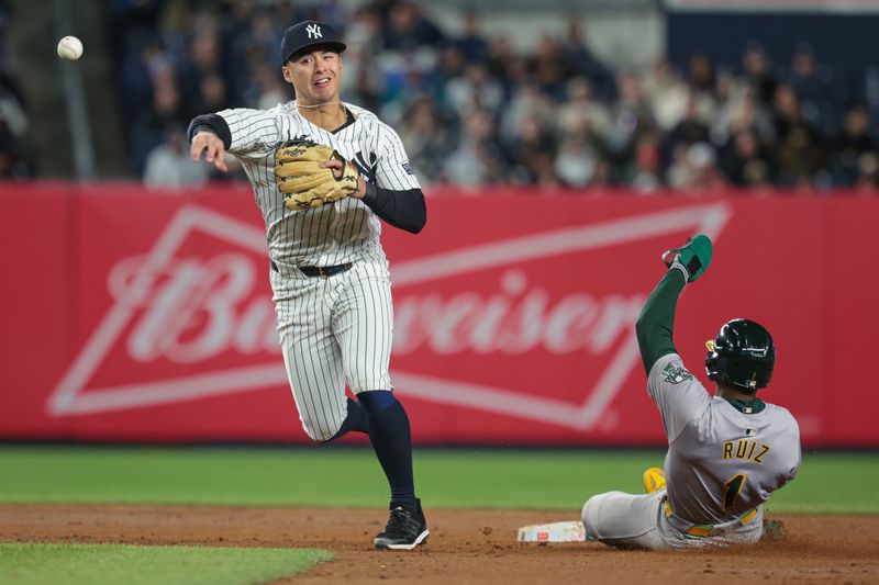 Apr 25, 2024; Bronx, New York, USA; New York Yankees shortstop Anthony Volpe (11) forces out Oakland Athletics left fielder Esteury Ruiz (1) at second base and throws to first base to complete the double play during the eighth inning at Yankee Stadium. Mandatory Credit: Vincent Carchietta-USA TODAY Sports