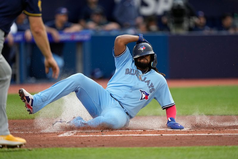 May 30, 2023; Toronto, Ontario, CAN; Toronto Blue Jays first baseman Vladimir Guerrero Jr. (27) slides into home plate on a two run double by left fielder Whit Merrifield (not pictured) against the Milwaukee Brewers during the first inning at Rogers Centre. Mandatory Credit: John E. Sokolowski-USA TODAY Sports