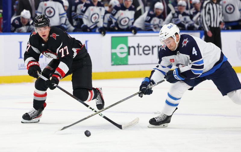 Mar 3, 2024; Buffalo, New York, USA;  Buffalo Sabres right wing JJ Peterka (77) and Winnipeg Jets defenseman Neal Pionk (4) go after a loose puck during the second period at KeyBank Center. Mandatory Credit: Timothy T. Ludwig-USA TODAY Sports