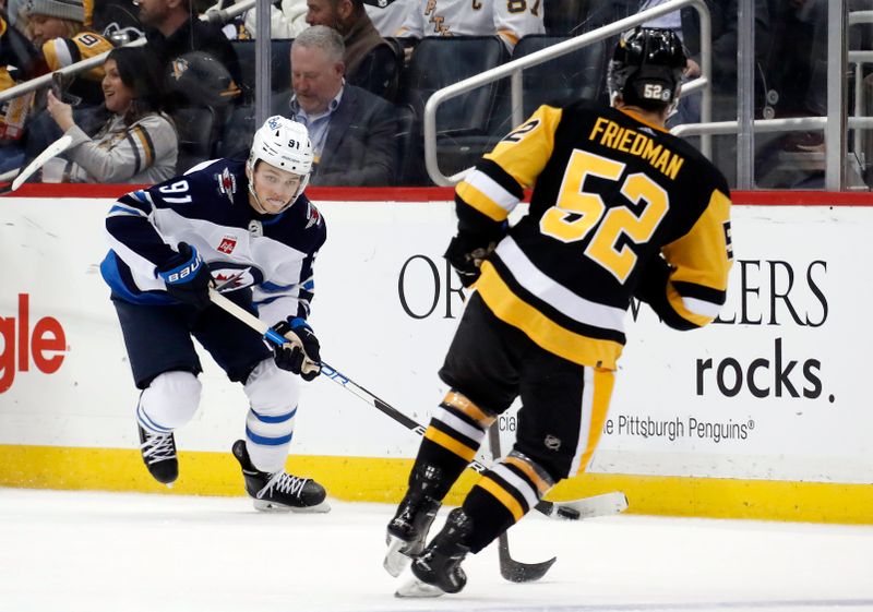 Jan 13, 2023; Pittsburgh, Pennsylvania, USA; Winnipeg Jets center Cole Perfetti (91) skates with the puck the puck as Pittsburgh Penguins defenseman Mark Friedman (52) defends during the second period at PPG Paints Arena. Mandatory Credit: Charles LeClaire-USA TODAY Sports