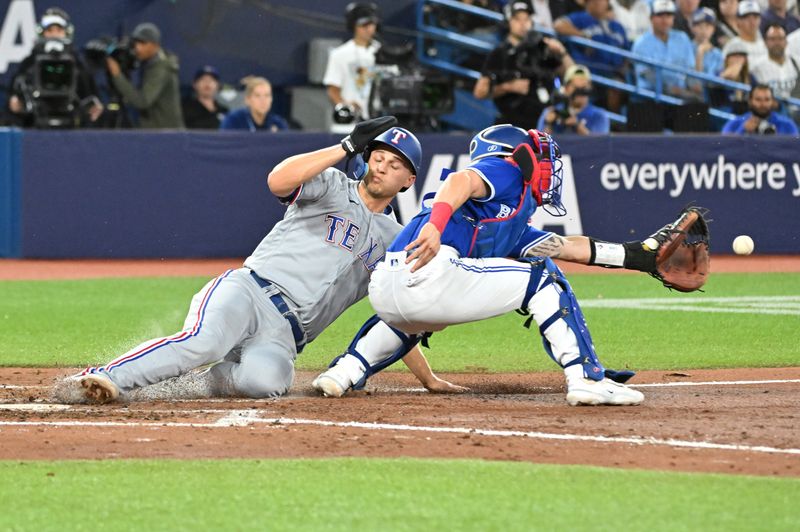 Sep 12, 2023; Toronto, Ontario, CAN;   Texas Rangers shortstop Corey Seager (5) slides home to score as Toronto Blue Jays catcher Tyer Heineman (55) reaches for the ball in the sixth inning at Rogers Centre. Mandatory Credit: Dan Hamilton-USA TODAY Sports