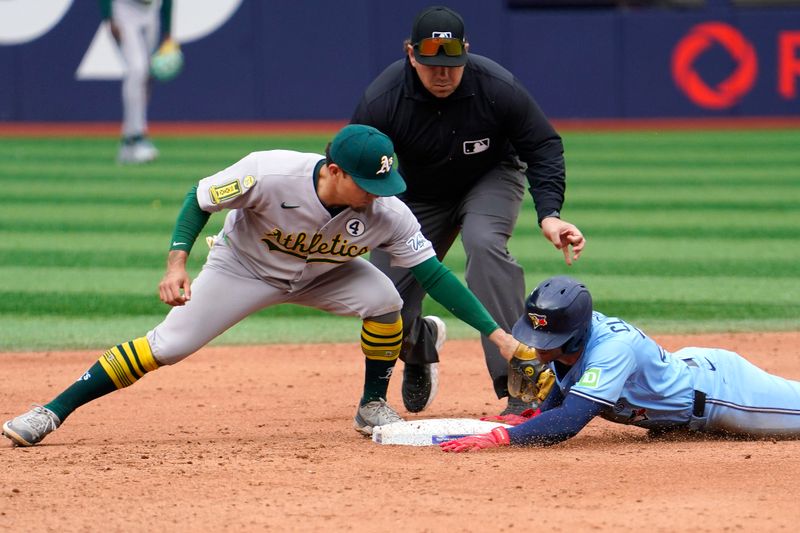 Jun 1, 2025; Toronto, Ontario, CAN; Toronto Blue Jays first baseman Ernie Clement (22) beats the tag from Oakland Athletics second baseman Luis Urias (17) to slide safely to second base on a double during the eighth inning at Rogers Centre. Mandatory Credit: John E. Sokolowski-Imagn Images