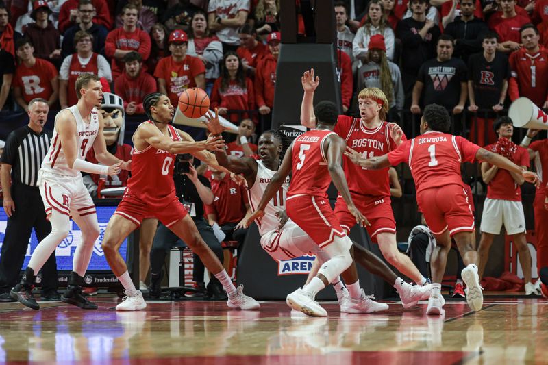 Nov 10, 2023; Piscataway, New Jersey, USA; Rutgers Scarlet Knights center Clifford Omoruyi (11) passes the ball while falling as Boston University Terriers forward Matai Baptiste (0) and guard Kyrone Alexander (5) defend during the first half at Jersey Mike's Arena. Mandatory Credit: Vincent Carchietta-USA TODAY Sports