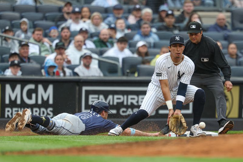 May 4, 2025; Bronx, New York, USA; Tampa Bay Rays shortstop Taylor Walls (6) slides safely back to third base as New York Yankees third baseman Oswaldo Cabrera (95) can to control a throw during the fifth inning at Yankee Stadium. Mandatory Credit: Vincent Carchietta-Imagn Images