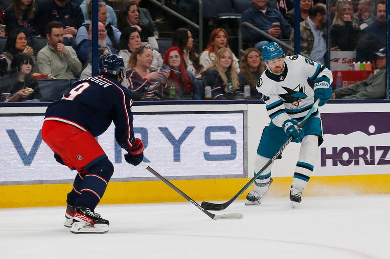 Mar 16, 2024; Columbus, Ohio, USA; San Jose Sharks  center Ryan Carpenter (22) passes the puck as Columbus Blue Jackets defenseman Ivan Provorov (9) defends during the first period at Nationwide Arena. Mandatory Credit: Russell LaBounty-USA TODAY Sports