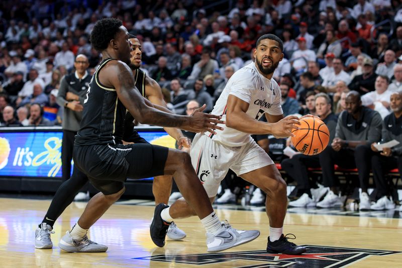 Feb 4, 2023; Cincinnati, Ohio, USA;  Cincinnati Bearcats guard David DeJulius (5) controls the ball against UCF Knights guard P.J. Edwards (left) and guard Darius Johnson (back) in the second half at Fifth Third Arena. Mandatory Credit: Aaron Doster-USA TODAY Sports