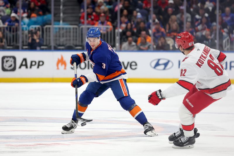 Jan 25, 2025; Elmont, New York, USA; New York Islanders defenseman Adam Pelech (3) plays the puck against Carolina Hurricanes center Jesperi Kotkaniemi (82) during the third period at UBS Arena. Mandatory Credit: Brad Penner-Imagn Images