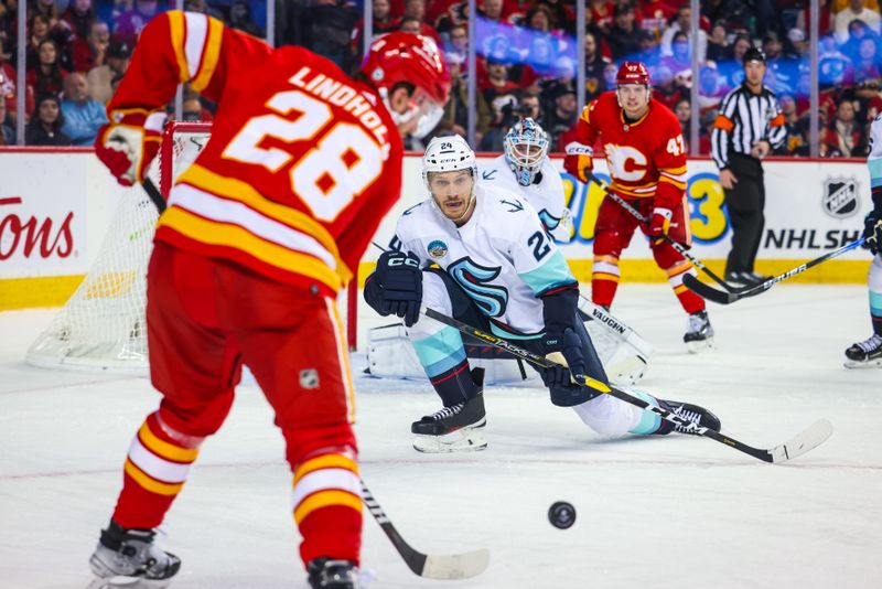 Dec 27, 2023; Calgary, Alberta, CAN; Seattle Kraken defenseman Jamie Oleksiak (24) goes to block a shot by Calgary Flames center Elias Lindholm (28) during the second period at Scotiabank Saddledome. Mandatory Credit: Sergei Belski-USA TODAY Sports