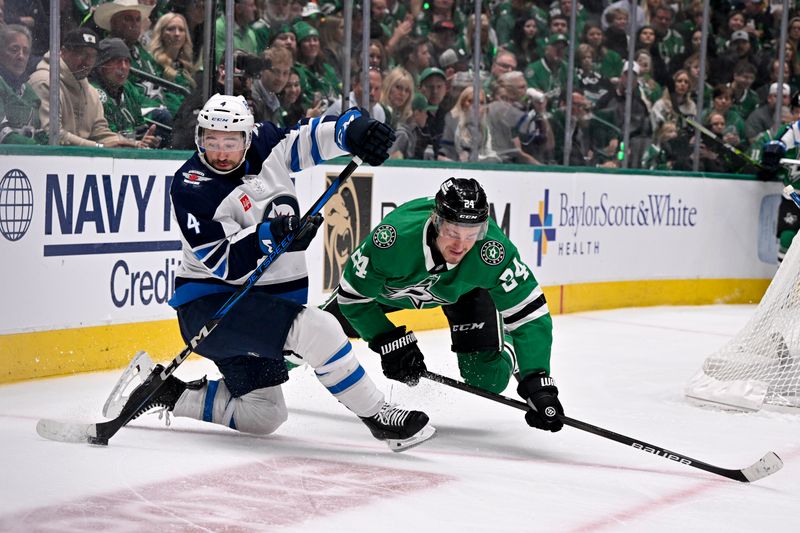May 11, 2025; Dallas, Texas, USA; Winnipeg Jets defenseman Neal Pionk (4) and d24 battles for control of the puck during the second period in game three of the second round of the 2025 Stanley Cup Playoffs at American Airlines Center. Mandatory Credit: Jerome Miron-Imagn Images