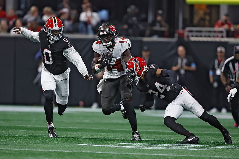 Tampa Bay Buccaneers wide receiver Chris Godwin (14) gets by Atlanta Falcons cornerback A.J. Terrell (24) and linebacker Lorenzo Carter (0) after a catch during the first half of an NFL football game Thursday, Oct. 3, 2024, in Atlanta. (AP Photo/Butch Dill)