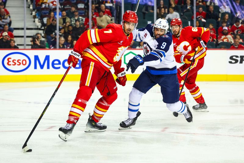 Oct 4, 2024; Calgary, Alberta, CAN; Calgary Flames defenseman Kevin Bahl (7) and Winnipeg Jets left wing Alex Iafallo (9) battles for the puck during the third period at Scotiabank Saddledome. Mandatory Credit: Sergei Belski-Imagn Images