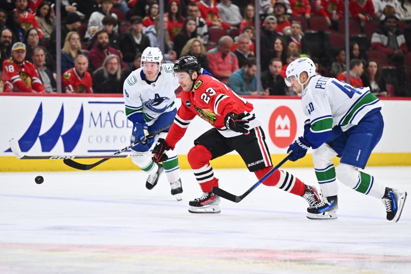 Feb 13, 2024; Chicago, Illinois, USA; Chicago Blackhawks forward Philipp Kurashev (23) races against Vancouver Canucks forward Brock Boeser (6) and forward Elias Pettersson (40) to a loose puck in the first period at United Center. Mandatory Credit: Jamie Sabau-USA TODAY Sports