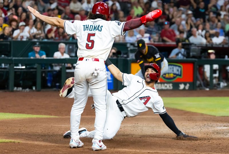May 27, 2025; Phoenix, Arizona, USA; Arizona Diamondbacks base runner Jordan Lawlar (right) celebrates with Alek Thomas as he slides into home to score against the Pittsburgh Pirates in the fourth inning at Chase Field. Mandatory Credit: Mark J. Rebilas-Imagn Images