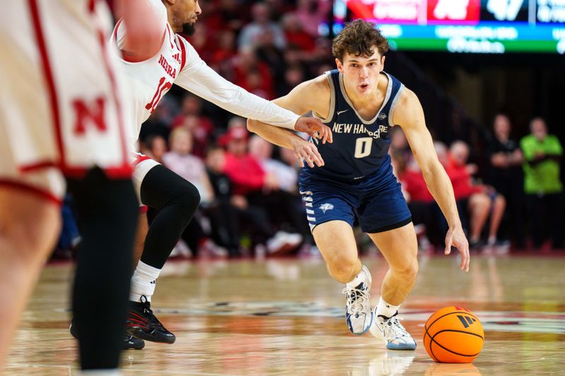 Dec 30, 2025; Lincoln, Nebraska, USA; New Hampshire Wildcats guard Tyler Bike (0) drives against Nebraska Cornhuskers guard Jamarques Lawrence (10) during the second half at Pinnacle Bank Arena. Mandatory Credit: Dylan Widger-Imagn Images