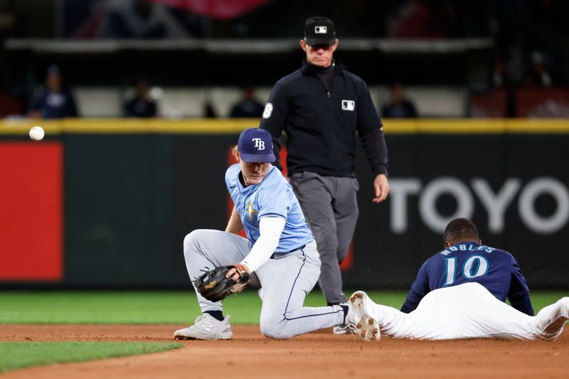 Aug 27, 2024; Seattle, Washington, USA; Tampa Bay Rays shortstop Taylor Walls (6) loses control of the ball while attempting a tag of Seattle Mariners center fielder Victor Robles (10) during a sixth inning stolen base attempt at T-Mobile Park. Mandatory Credit: Joe Nicholson-USA TODAY Sports