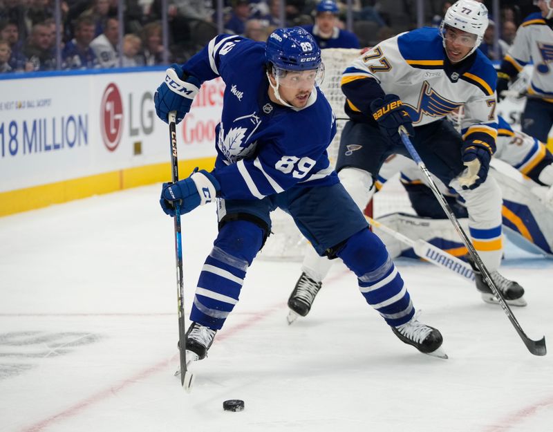 Oct 24, 2024; Toronto, Ontario, CAN; Toronto Maple Leafs forward Nicholas Robertson (89) controls the puck against St. Louis Blues defenseman Pierre-Olivier Joseph (77) during the third period at Scotiabank Arena. Mandatory Credit: John E. Sokolowski-Imagn Images