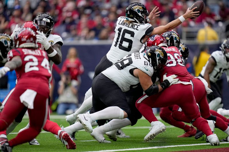 Jacksonville Jaguars quarterback Trevor Lawrence (16) extends the ball over the goal line for a touchdown as Lawrence gets help from guard Brandon Scherff (68) against Houston Texans defensive tackle Sheldon Rankins on the score in the first half of an NFL football game in Houston, Sunday, Nov. 26, 2023. (AP Photo/Eric Gay)