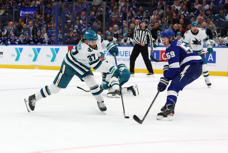 Dec 5, 2024; Tampa, Florida, USA; San Jose Sharks defenseman Timothy Liljegren (37) shoots as Tampa Bay Lightning center Jake Guentzel (59) defends during the second period at Amalie Arena. Mandatory Credit: Kim Klement Neitzel-Imagn Images