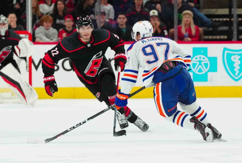 Nov 22, 2023; Raleigh, North Carolina, USA; Carolina Hurricanes defenseman Brett Pesce (22) watches Edmonton Oilers center Connor McDavid (97) skated tie the puck during the third period at PNC Arena. Mandatory Credit: James Guillory-USA TODAY Sports