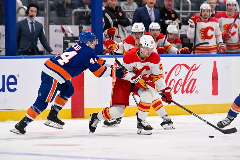 Mar 22, 2025; Elmont, New York, USA; New York Islanders center Jean-Gabriel Pageau (44) defends against Calgary Flames center Connor Zary (47) during the first period at UBS Arena. Mandatory Credit: Dennis Schneidler-Imagn Images