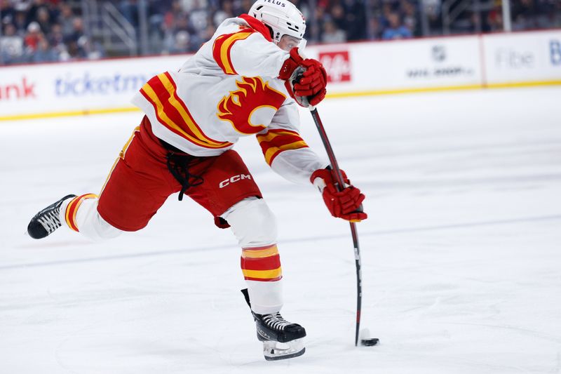 Jan 26, 2025; Winnipeg, Manitoba, CAN;  Calgary Flames forward Jacob Pelletier (22) takes a shot on the Winnipeg Jets net during the first period at Canada Life Centre. Mandatory Credit: Terrence Lee-Imagn Images