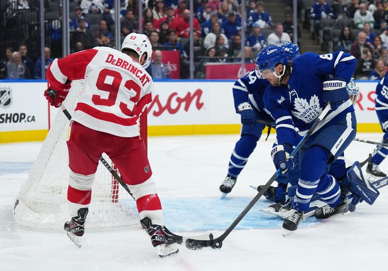 Oct 2, 2025; Toronto, Ontario, CAN; Toronto Maple Leafs defenseman Chris Tanev (8) battles for the puck with Detroit Red Wings right wing Alex DeBrincat (93) during the second period at Scotiabank Arena. Mandatory Credit: Nick Turchiaro-Imagn Images