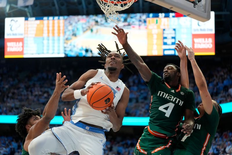 Feb 26, 2024; Chapel Hill, North Carolina, USA; North Carolina Tar Heels forward Jae'Lyn Withers (24) with the ball as Miami (Fl) Hurricanes forward Norchad Omier (15) and guard Bensley Joseph (4) and guard Kyshawn George (7) defend in the second half at Dean E. Smith Center. Mandatory Credit: Bob Donnan-USA TODAY Sports