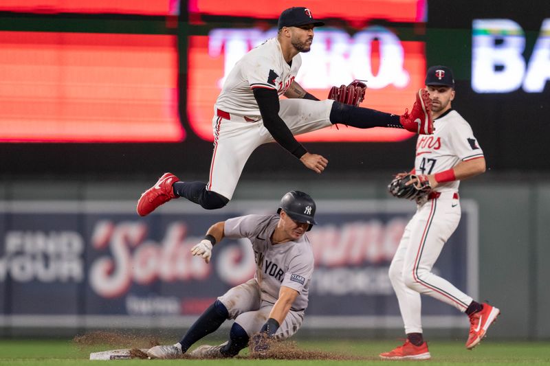 May 15, 2024; Minneapolis, Minnesota, USA; Minnesota Twins shortstop Carlos Correa (4) leaps over New York Yankees shortstop Anthony Volpe (11) to complete the double play on a ball hit by New York Yankees right fielder Juan Soto (22) at Target Field. Mandatory Credit: Matt Blewett-USA TODAY Sports