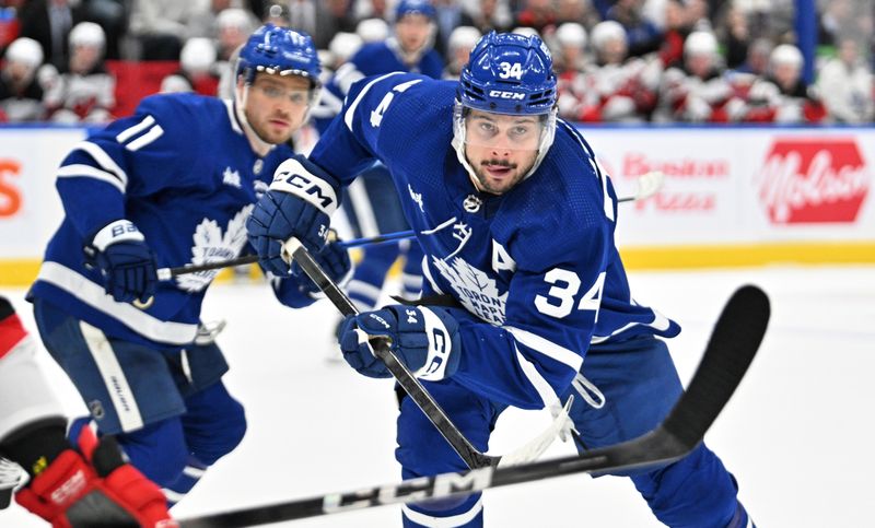 Apr 11, 2024; Toronto, Ontario, CAN; Toronto Maple Leafs forward Auston Matthews (34) pursues the play ahead of forward Max Domi (11) against the New Jersey Devils in the first period at Scotiabank Arena. Mandatory Credit: Dan Hamilton-USA TODAY Sports