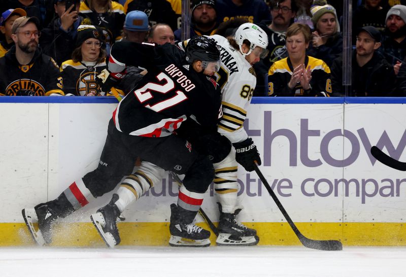 Dec 27, 2023; Buffalo, New York, USA;  Buffalo Sabres right wing Kyle Okposo (21) checks Boston Bruins right wing David Pastrnak (88) as he goes after the puck during the first period at KeyBank Center. Mandatory Credit: Timothy T. Ludwig-USA TODAY Sports