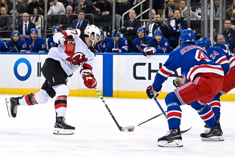 Dec 2, 2024; New York, New York, USA;  New Jersey Devils center Paul Cotter (47) shoots as New York Rangers defenseman Braden Schneider (4) and right wing Kaapo Kakko (24) defend during the first period at Madison Square Garden. Mandatory Credit: Dennis Schneidler-Imagn Images