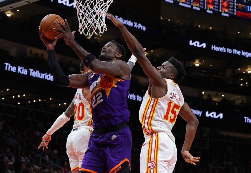 ATLANTA, GEORGIA - FEBRUARY 09:  Deandre Ayton #22 of the Phoenix Suns drives against Clint Capela #15 and John Collins #20 of the Atlanta Hawks during the fourth quarter at State Farm Arena on February 09, 2023 in Atlanta, Georgia.  NOTE TO USER: User expressly acknowledges and agrees that, by downloading and or using this photograph, User is consenting to the terms and conditions of the Getty Images License Agreement. (Photo by Kevin C. Cox/Getty Images)