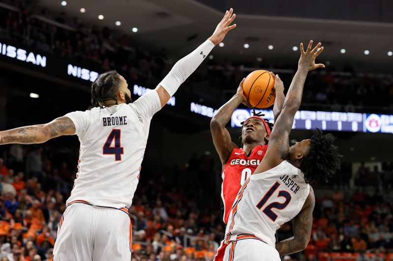 Feb 1, 2023; Auburn, Alabama, USA;  Georgia Bulldogs guard Terry Roberts (0) goes for a shot between Auburn Tigers forward Johni Broome (4) and guard Zep Jasper (12) during the first half at Neville Arena. Mandatory Credit: John Reed-USA TODAY Sports