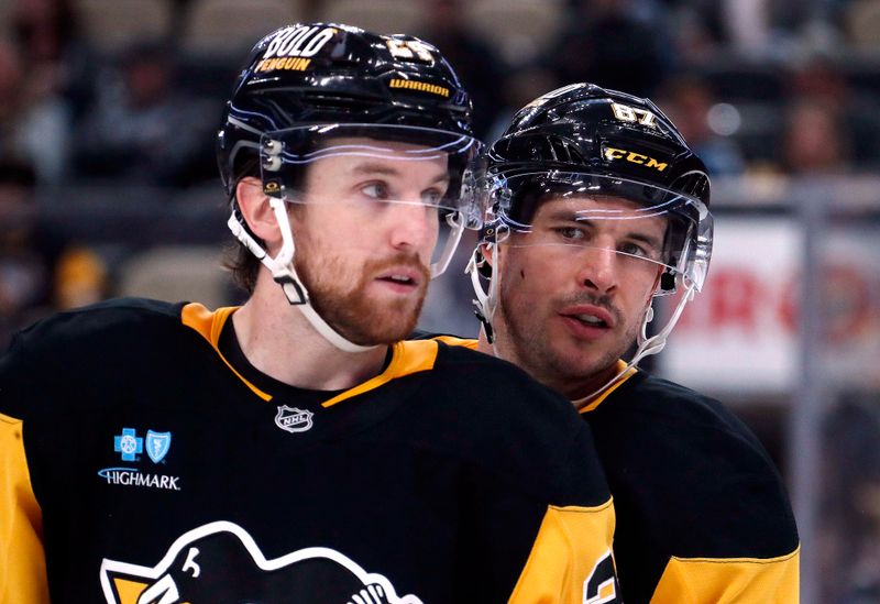 Oct 16, 2024; Pittsburgh, Pennsylvania, USA; Pittsburgh Penguins defenseman Matt Grzelcyk (left) listens to center Sidney Crosby (right) before a face-off against the Buffalo Sabres during the third period at PPG Paints Arena. Mandatory Credit: Charles LeClaire-Imagn Images