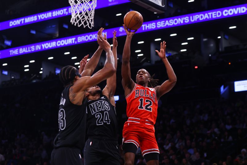 NEW YORK, NEW YORK - MARCH 29: Ayo Dosunmu #12 of the Chicago Bulls attempts a basket against Cam Thomas #24 of the Brooklyn Nets at Barclays Center on March 29, 2024 in New York City. NOTE TO USER: User expressly acknowledges and agrees that, by downloading and or using this photograph, User is consenting to the terms and conditions of the Getty Images License Agreement.   (Photo by Mike Stobe/Getty Images)