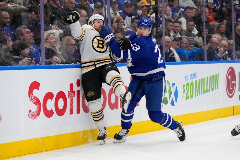 Mar 4, 2024; Toronto, Ontario, CAN; Toronto Maple Leafs forward Matthew Knies (23) checks Boston Bruins defenseman Matt Grzelcyk (48) into the boards during the first period at Scotiabank Arena. Mandatory Credit: John E. Sokolowski-USA TODAY Sports