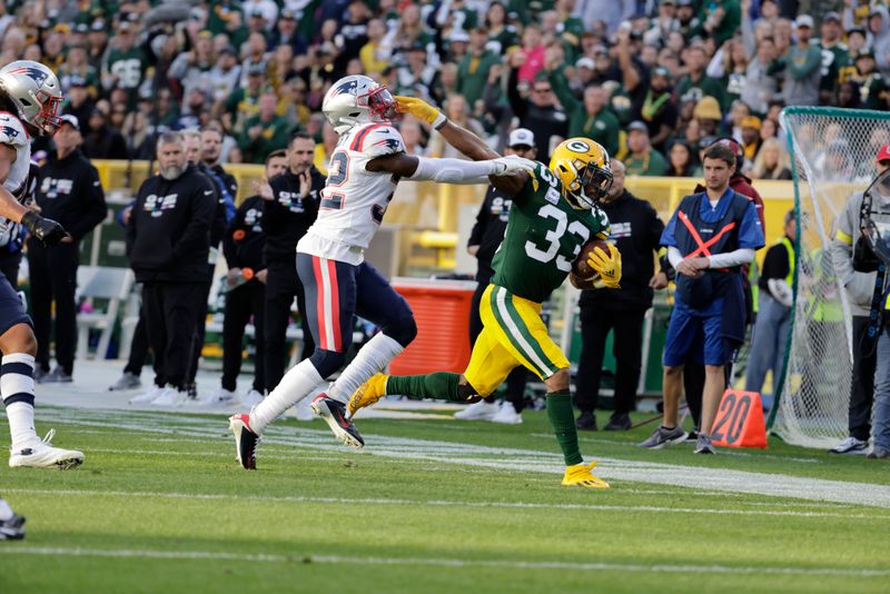 Green Bay Packers running back Aaron Jones (33) gets forced out of bounds by New England Patriots safety Devin McCourty (32) during an NFL football game Sunday, Oct. 2, 2022, in Green Bay, Wis. (AP Photo/Mike Roemer)